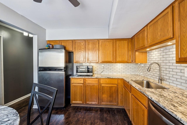 kitchen with sink, tasteful backsplash, light stone counters, dark hardwood / wood-style floors, and stainless steel appliances