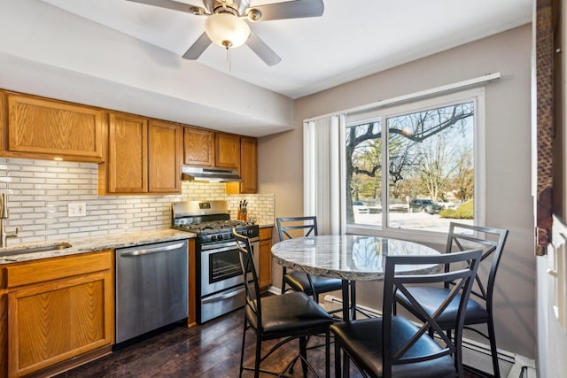 kitchen featuring light stone countertops, dark hardwood / wood-style flooring, stainless steel appliances, decorative backsplash, and sink