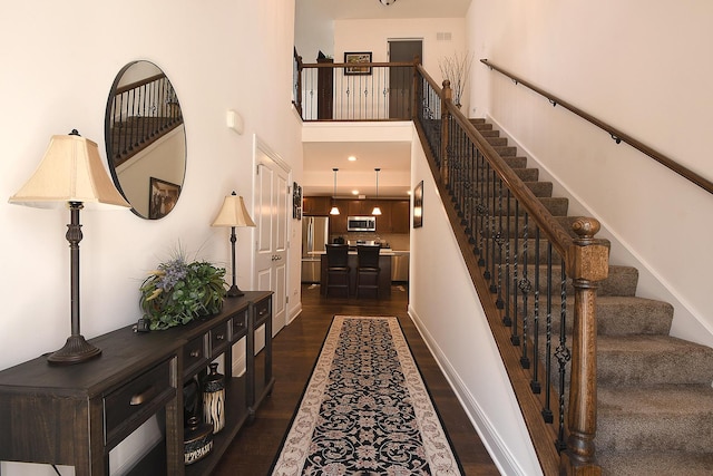 stairway featuring hardwood / wood-style floors and a towering ceiling