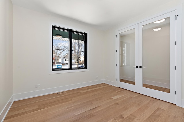 unfurnished room with french doors, visible vents, light wood-style flooring, and baseboards