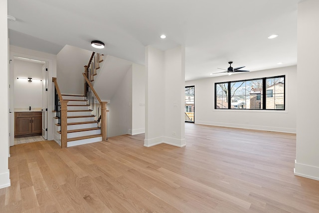 unfurnished living room with light wood-style flooring, stairway, baseboards, and recessed lighting