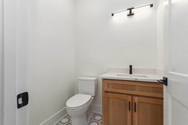 half bath featuring toilet, tile patterned flooring, baseboards, and vanity