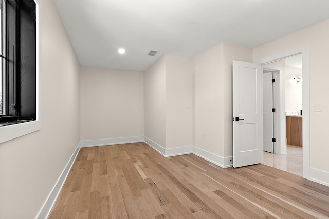 empty room featuring light wood finished floors, baseboards, and visible vents