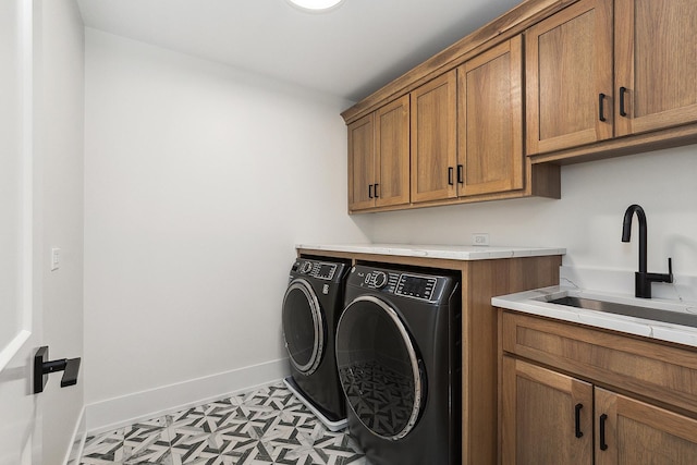 laundry area featuring cabinet space, baseboards, separate washer and dryer, and a sink