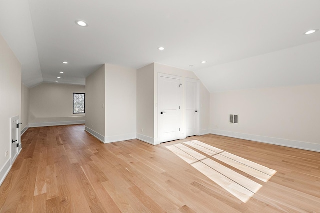 additional living space with recessed lighting, visible vents, baseboards, vaulted ceiling, and light wood finished floors