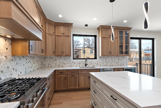 kitchen featuring brown cabinetry, a wealth of natural light, premium range hood, and a sink