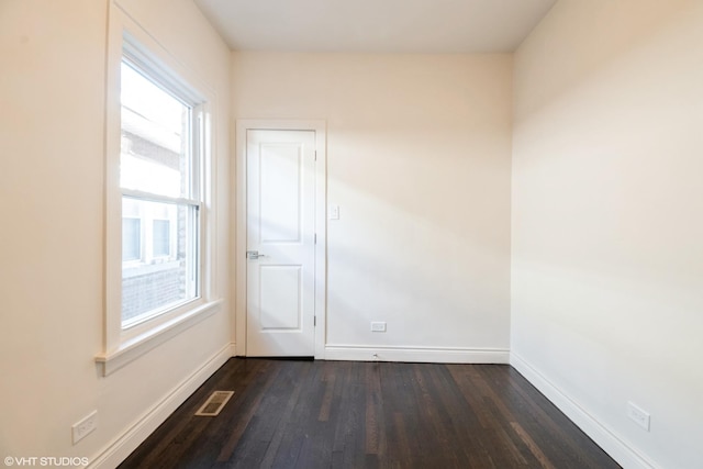 spare room featuring a wealth of natural light and dark hardwood / wood-style floors