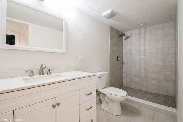 bathroom with tiled shower, vanity, toilet, and tile patterned floors