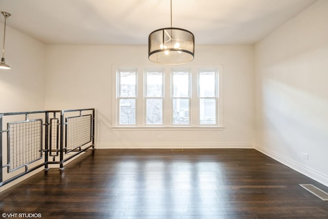 unfurnished room with dark hardwood / wood-style floors, a wealth of natural light, and an inviting chandelier