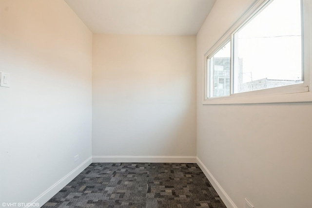 spare room featuring dark colored carpet