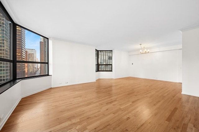 empty room with a chandelier and light hardwood / wood-style flooring