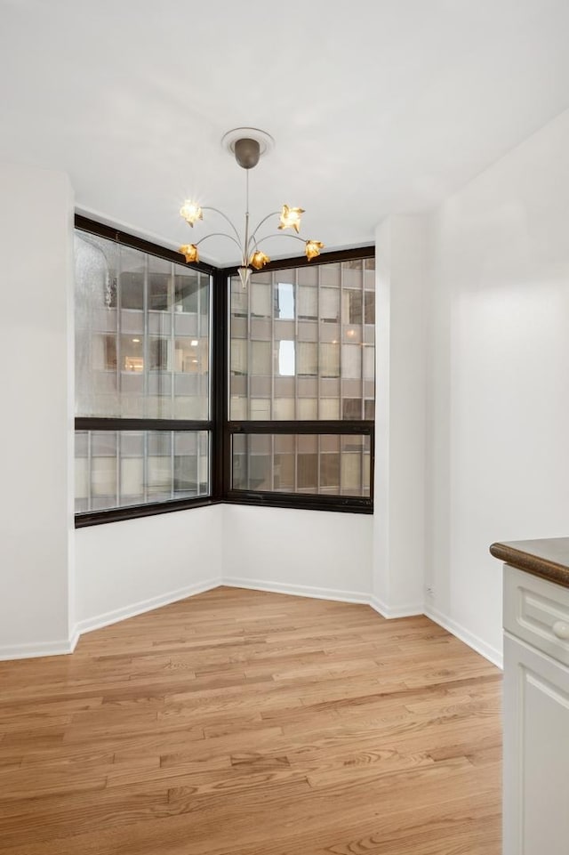 unfurnished dining area featuring light hardwood / wood-style floors and a chandelier