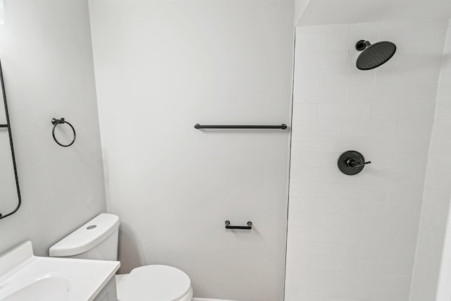 bathroom with vanity, toilet, and a tile shower