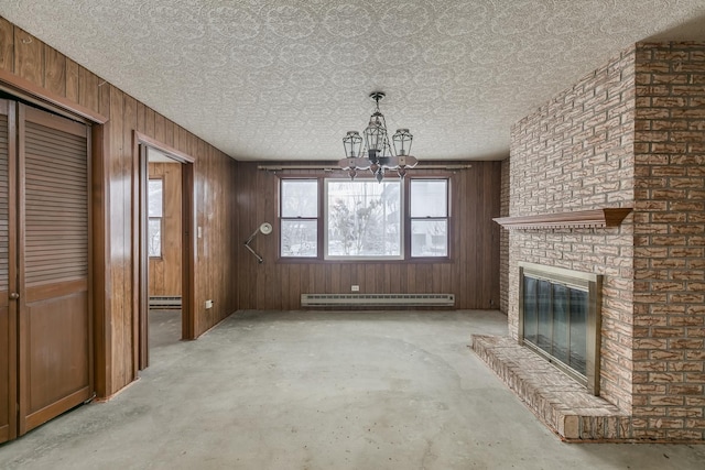 unfurnished living room featuring a chandelier, wood walls, a fireplace, and a baseboard radiator