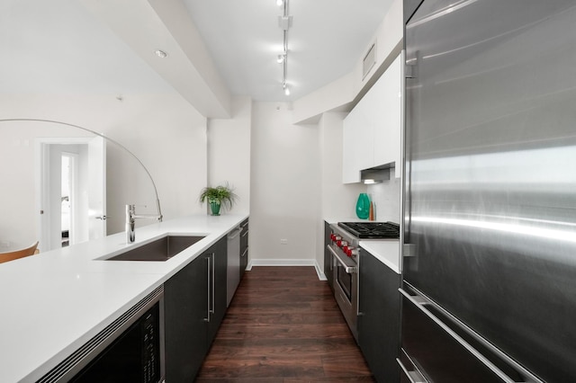 kitchen with sink, white cabinetry, track lighting, dark hardwood / wood-style floors, and appliances with stainless steel finishes