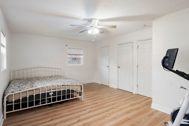 bedroom with multiple closets, ceiling fan, a textured ceiling, and hardwood / wood-style flooring