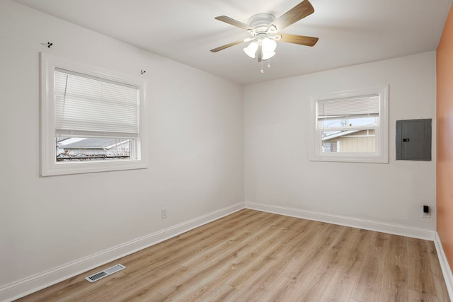 spare room with ceiling fan, electric panel, and light hardwood / wood-style flooring