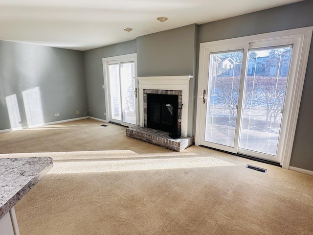 unfurnished living room featuring light colored carpet and a brick fireplace