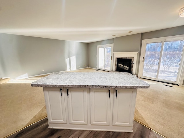 kitchen with white cabinets, a center island, and dark wood-type flooring