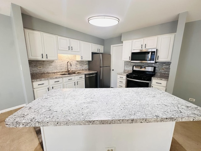 kitchen with white cabinets, decorative backsplash, stainless steel appliances, and sink