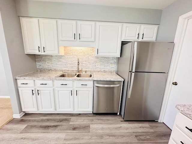 kitchen featuring tasteful backsplash, stainless steel appliances, sink, light hardwood / wood-style floors, and white cabinetry