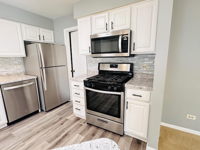 kitchen featuring decorative backsplash, appliances with stainless steel finishes, white cabinetry, and light stone counters