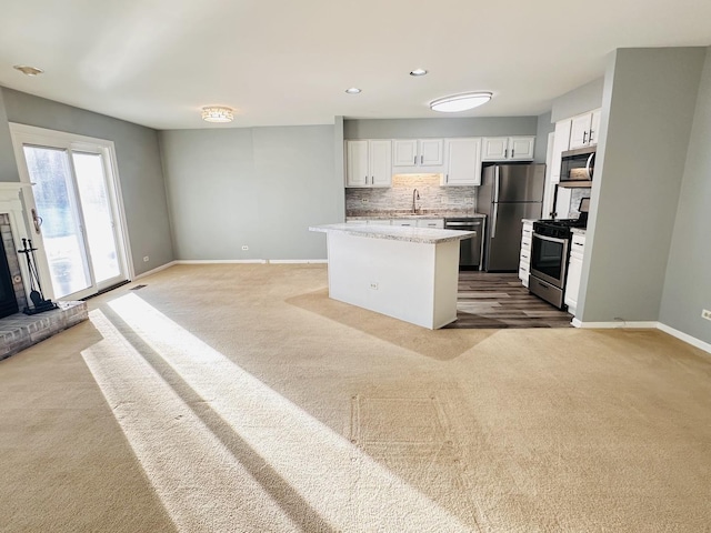 kitchen with light colored carpet, white cabinetry, sink, and appliances with stainless steel finishes