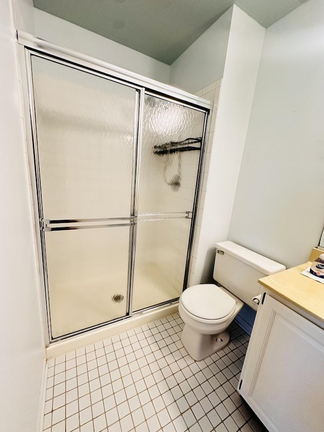 bathroom with tile patterned flooring, vanity, a shower with shower door, and toilet