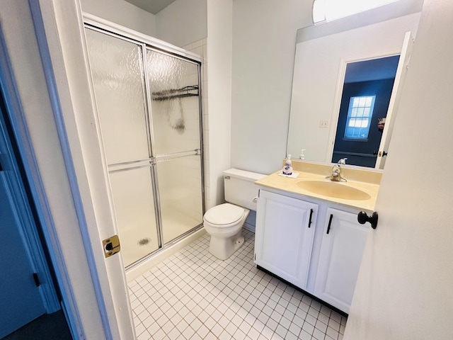 bathroom featuring tile patterned flooring, vanity, toilet, and a shower with door