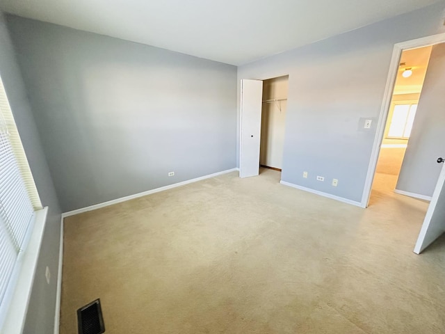 unfurnished bedroom featuring light colored carpet and a closet