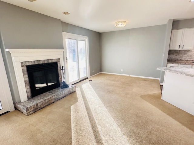 unfurnished living room featuring light colored carpet and a brick fireplace