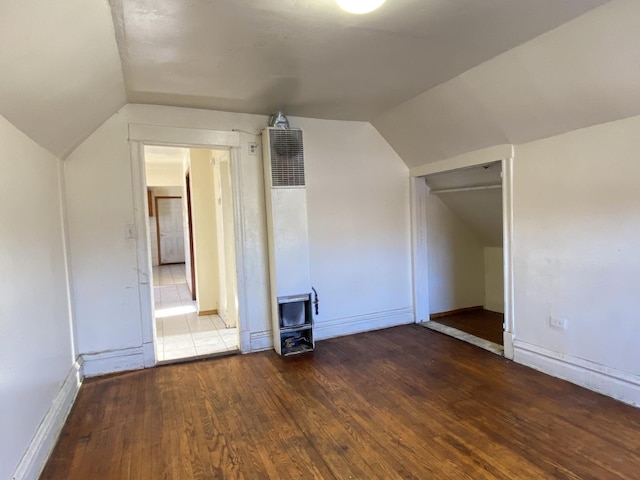 additional living space with dark hardwood / wood-style flooring and vaulted ceiling