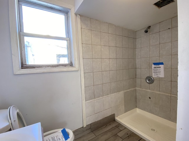 bathroom with toilet and a tile shower