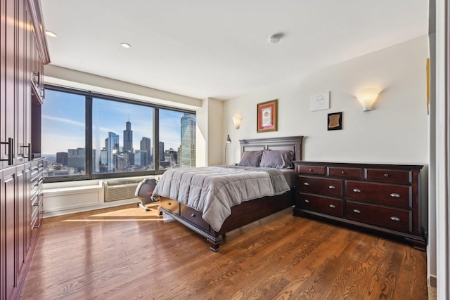 bedroom featuring dark wood-type flooring and a city view