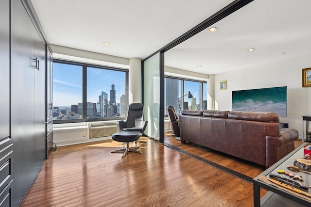 living room with a wall mounted AC, wood finished floors, and recessed lighting