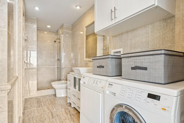 washroom with recessed lighting, laundry area, separate washer and dryer, a sink, and tile walls