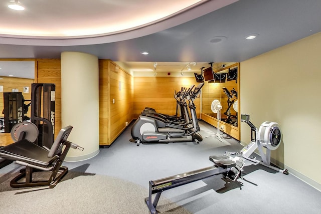 exercise room with baseboards, recessed lighting, and wooden walls