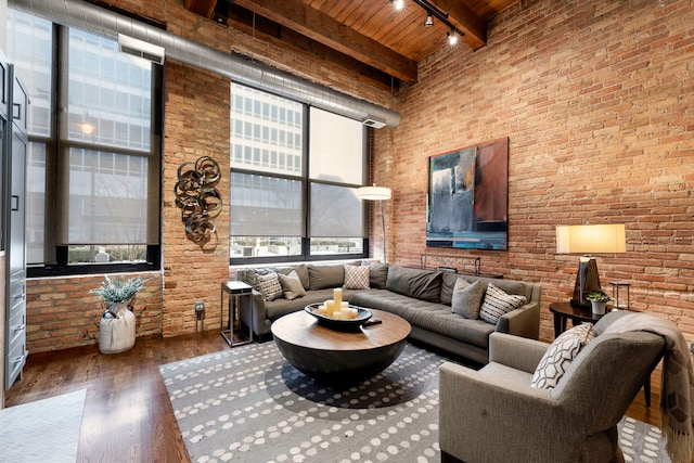 living room featuring wood ceiling, a towering ceiling, brick wall, and beamed ceiling