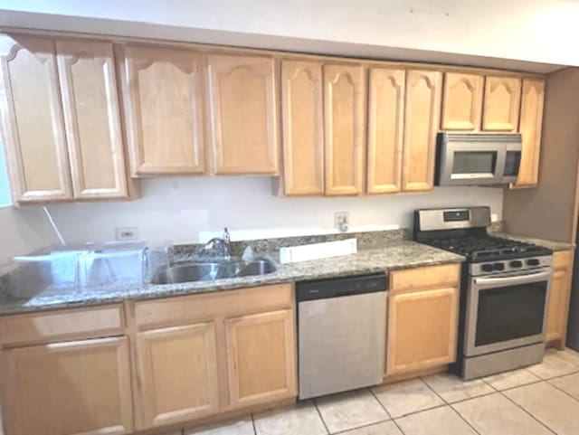 kitchen with stone countertops, appliances with stainless steel finishes, light brown cabinets, and light tile patterned flooring