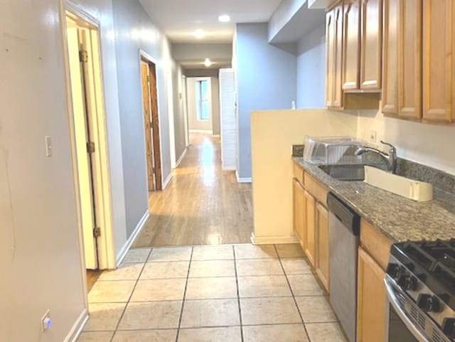 kitchen with light tile patterned floors, sink, appliances with stainless steel finishes, and dark stone countertops