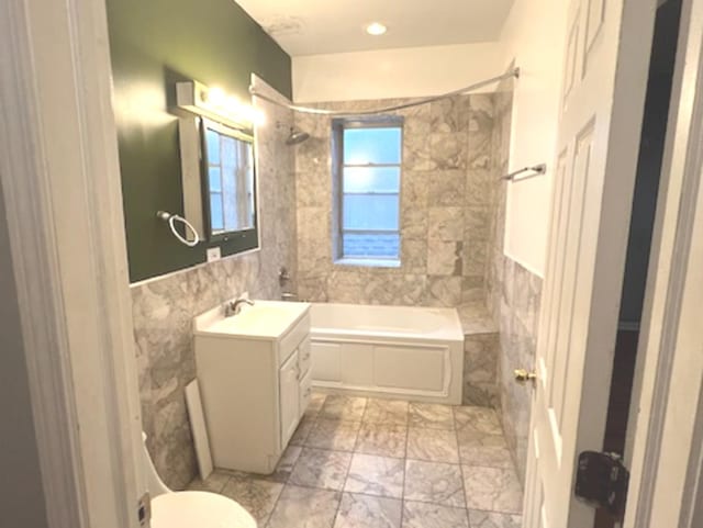 full bathroom featuring tile walls, toilet, vanity, and tiled shower / bath