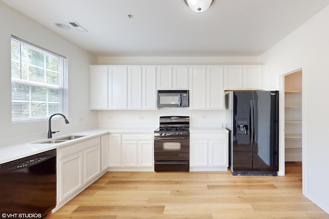 kitchen with sink, white cabinetry, light wood-type flooring, and black appliances