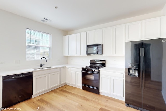 kitchen with black appliances, light hardwood / wood-style floors, white cabinetry, and sink