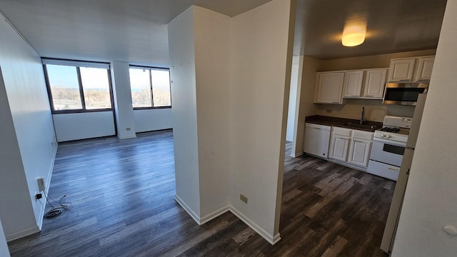 kitchen with sink, white cabinets, dark wood-type flooring, and white appliances