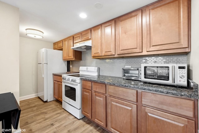 kitchen featuring white appliances, dark stone counters, light wood-type flooring, and decorative backsplash