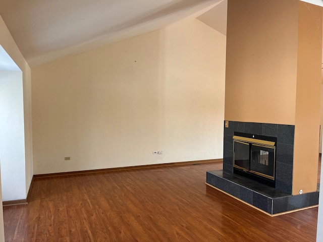 unfurnished living room featuring hardwood / wood-style flooring, vaulted ceiling, and a tiled fireplace