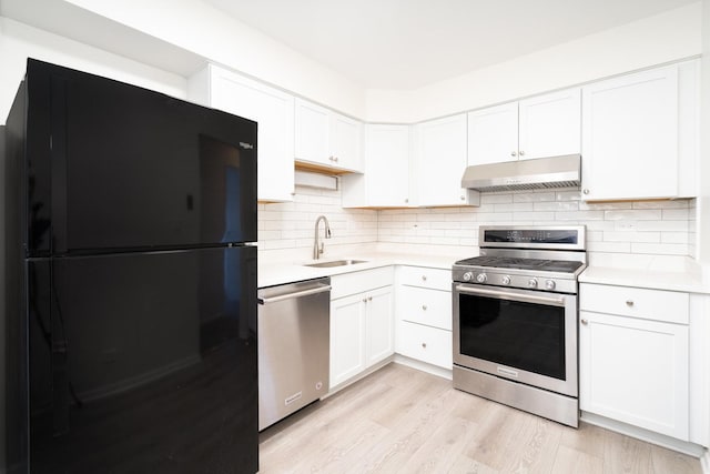 kitchen featuring stainless steel appliances, light wood-type flooring, sink, white cabinets, and tasteful backsplash