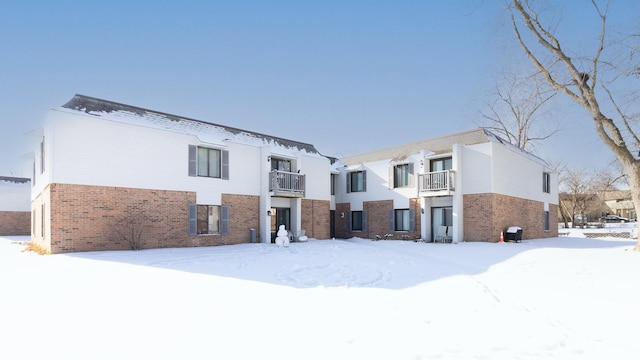 snow covered house featuring a balcony