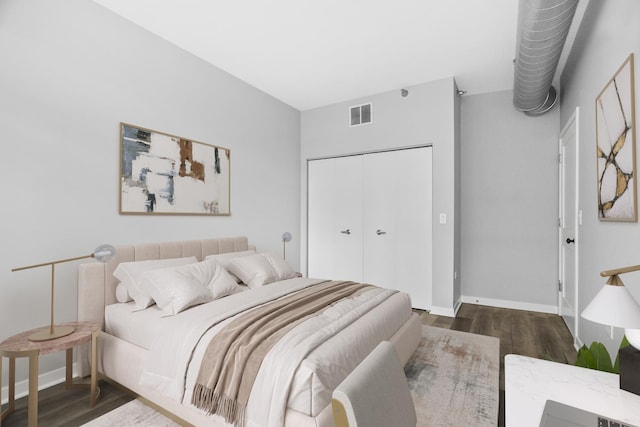 bedroom with dark hardwood / wood-style flooring and a closet