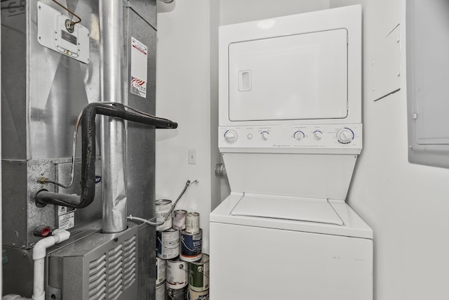 washroom featuring stacked washer and clothes dryer, heating unit, and electric panel